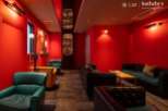 Luxurious red-walled lounge with plush leather seating and a built-in bar showcasing an impressive liquor collection.