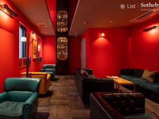 Luxurious red-walled lounge with plush leather seating and a built-in bar showcasing an impressive liquor collection.