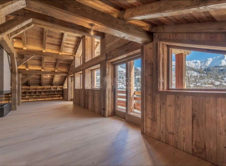 This stunning chalet boasts a spacious open-plan living area with exposed wooden beams and large windows offering breathtaking mountain views.