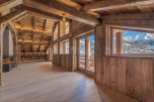This stunning chalet boasts a spacious open-plan living area with exposed wooden beams and large windows offering breathtaking mountain views.