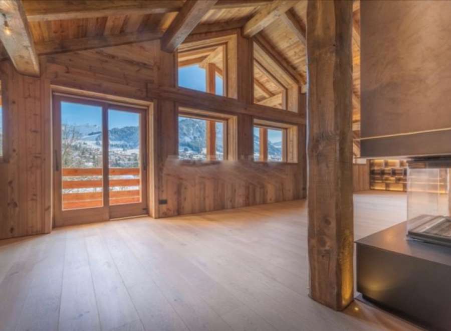 This stunning chalet boasts a spacious open-plan living area with floor-to-ceiling windows offering breathtaking mountain views.
