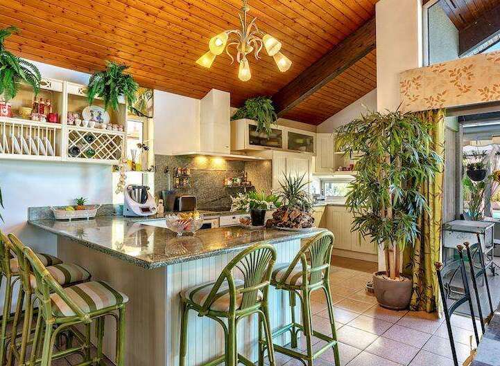 This stunning kitchen boasts a granite countertop island with bamboo barstools, creating a tropical vibe.