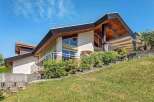 Stunning contemporary home nestled on a hillside, boasting expansive windows and a spacious outdoor terrace.