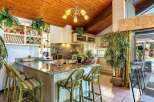 This stunning kitchen boasts a granite countertop island with bamboo barstools, creating a tropical vibe.