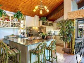 This stunning kitchen boasts a granite countertop island with bamboo barstools, creating a tropical vibe.