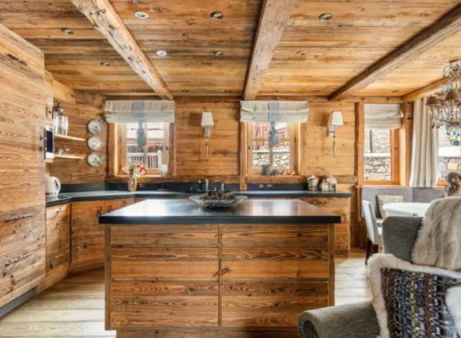 This stunning chalet boasts a rustic-chic kitchen with exposed wood beams, custom cabinetry, and a large island.