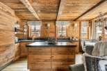 This stunning chalet boasts a rustic-chic kitchen with exposed wood beams, custom cabinetry, and a large island.