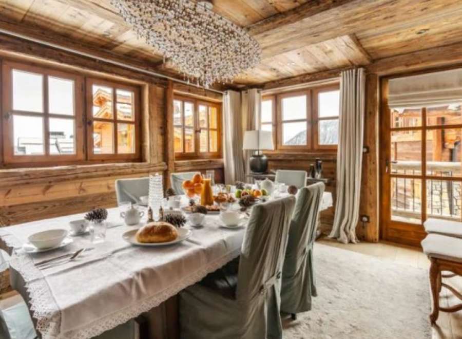 This stunning chalet boasts a spacious dining area with large windows offering breathtaking mountain views.