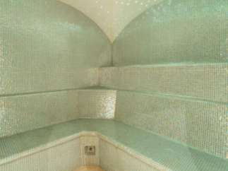 Relax and rejuvenate in this luxurious steam room, featuring stunning iridescent mosaic tile and a calming, softly lit atmosphere.