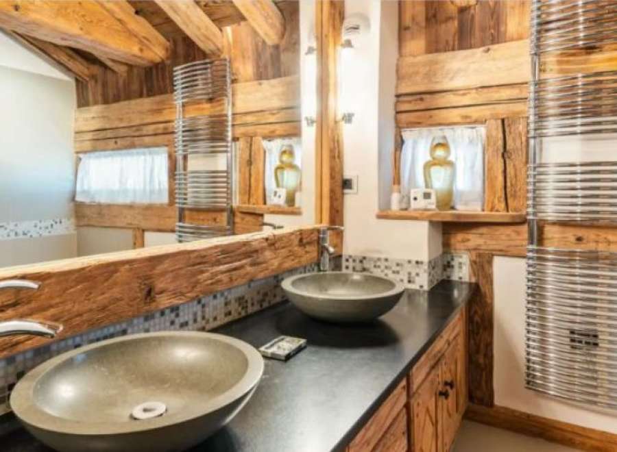 Rustic-chic bathroom boasts double sinks and heated towel racks.
