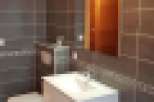 Modern bathroom with dark gray tiles, white vanity, and a built-in toilet.