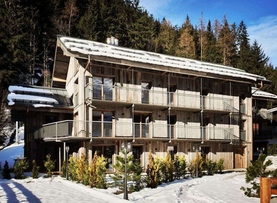 Discover a charming wooden chalet nestled in a snowy landscape.