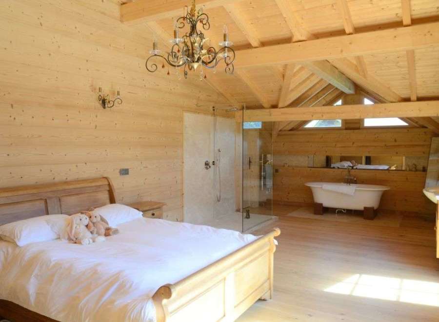 Luxurious chalet bedroom with ensuite bathroom featuring a freestanding bathtub and walk-in shower.