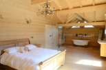 Luxurious chalet bedroom with ensuite bathroom featuring a freestanding bathtub and walk-in shower.