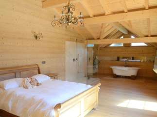 Luxurious chalet bedroom with ensuite bathroom featuring a freestanding bathtub and walk-in shower.