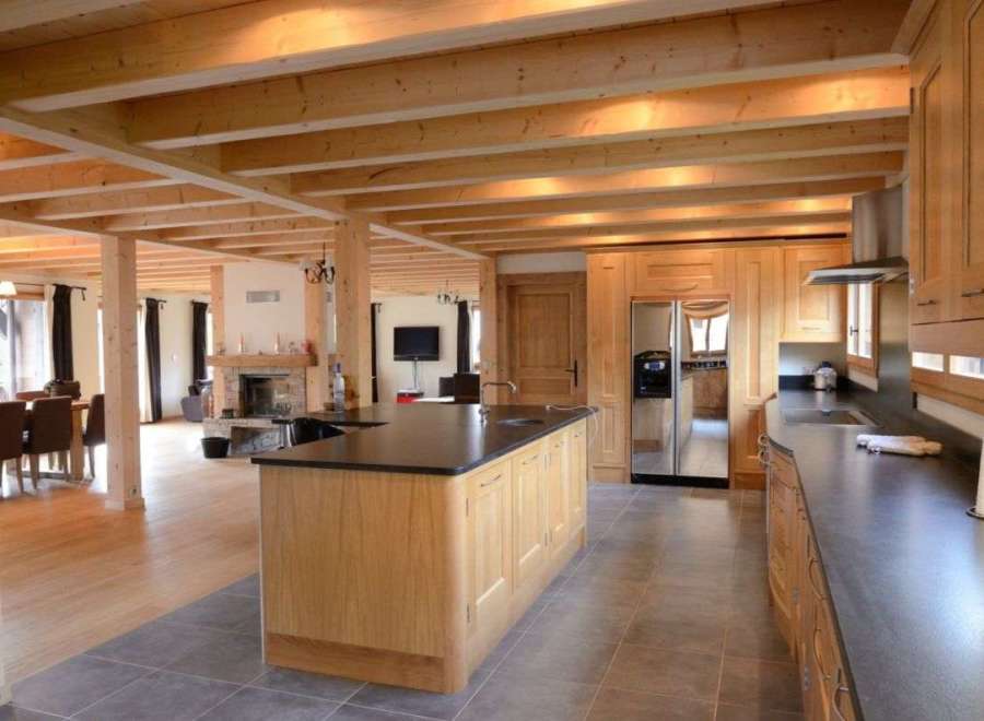This stunning chalet boasts a spacious open-plan living area with exposed wooden beams and large windows, creating a bright and airy atmosphere.
