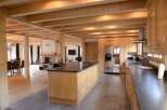 This stunning chalet boasts a spacious open-plan living area with exposed wooden beams and large windows, creating a bright and airy atmosphere.