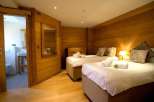 Cozy chalet bedroom with twin beds, ensuite bathroom, and wooden walls.