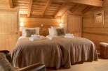 Cozy chalet bedroom with twin beds, wooden walls, and a rustic feel.