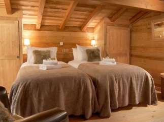 Cozy chalet bedroom with twin beds, wooden walls, and a rustic feel.