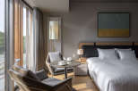 This hotel room boasts a modern design with floor-to-ceiling windows offering scenic views, creating a bright and airy atmosphere.