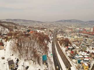 Explore the stunning winter landscape of Otaru, Japan, with this aerial view showcasing a modern highway cutting through a snow-covered town.