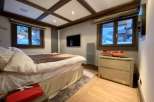 Luxury chalet bedroom with stunning mountain views, featuring a comfortable king-size bed and modern ensuite bathroom.
