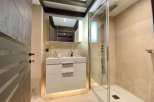 Modern bathroom with a walk-in shower, sleek white vanity, and elegant wood beam ceiling.