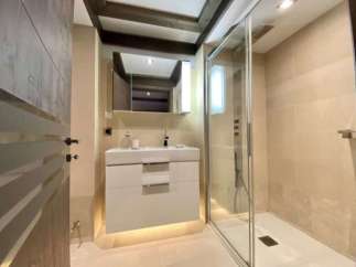 Modern bathroom with a walk-in shower, sleek white vanity, and elegant wood beam ceiling.