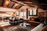 This stunning chalet boasts a spacious open-plan living area with exposed wooden beams and a cozy fireplace, creating a warm and inviting atmosphere.
