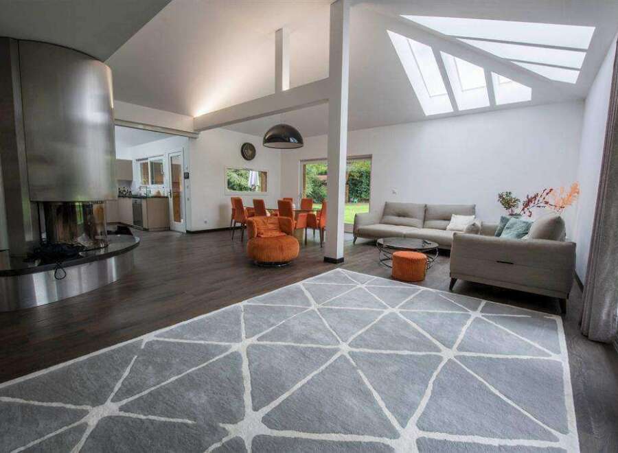 Stunning open-plan living area with a contemporary fireplace and large windows offering ample natural light.