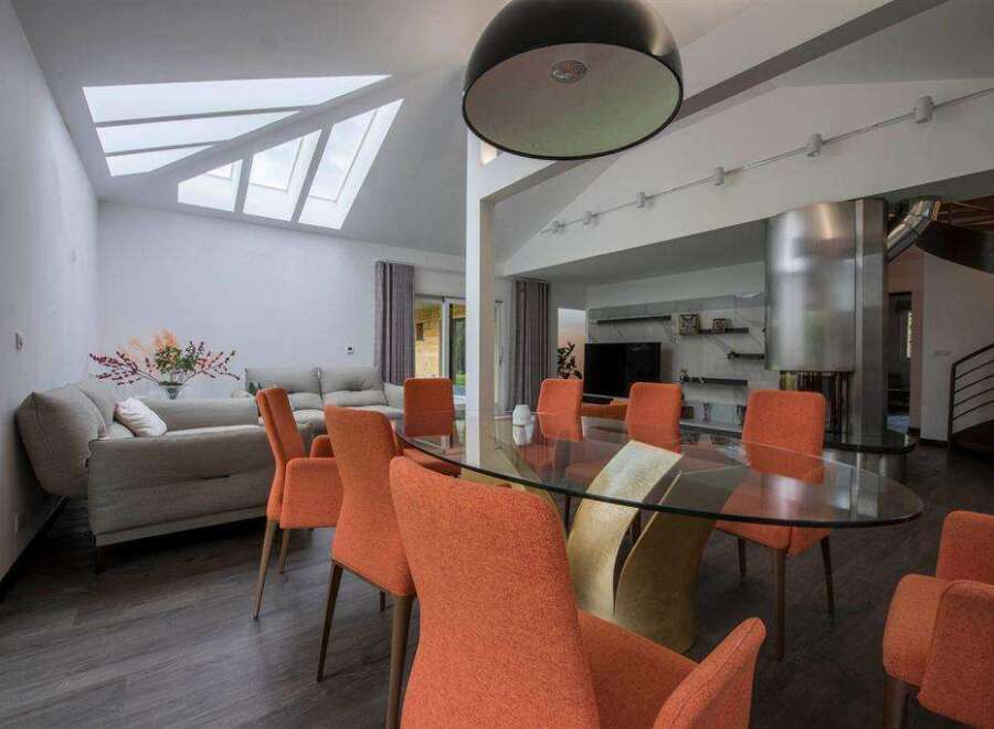 Stunning contemporary home boasts a spacious open-plan living area with a glass dining table and stylish orange chairs.