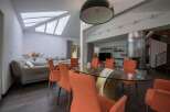 Stunning contemporary home boasts a spacious open-plan living area with a glass dining table and stylish orange chairs.