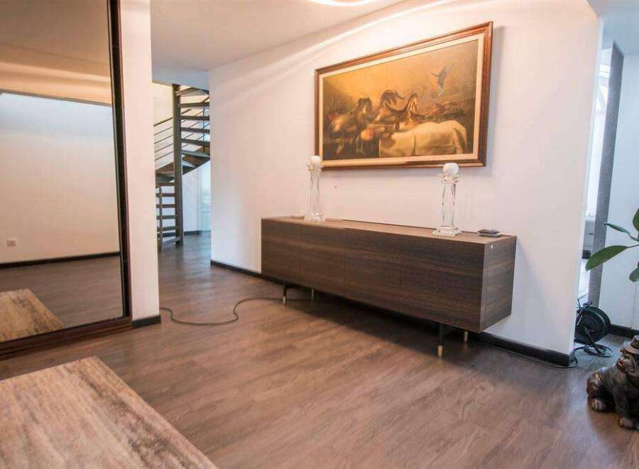 This stunning property boasts a spacious hallway with gleaming hardwood floors, a stylish sideboard, and elegant décor.