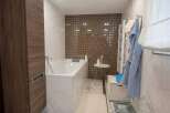Luxurious bathroom with a freestanding bathtub, marble flooring, and a stylish mosaic tile feature wall.
