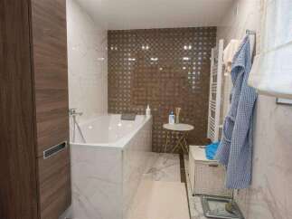 Luxurious bathroom with a freestanding bathtub, marble flooring, and a stylish mosaic tile feature wall.