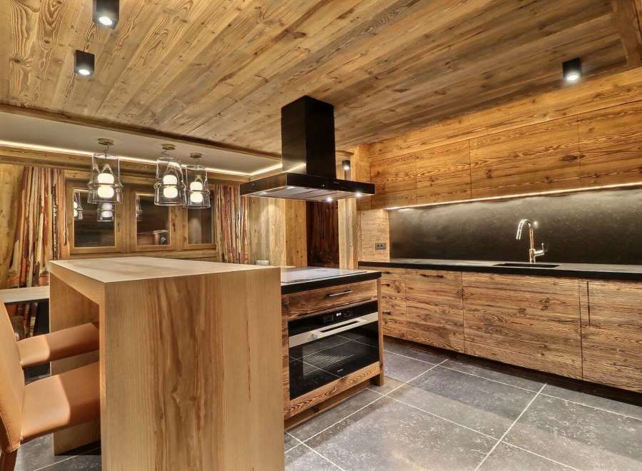 This stunning chalet boasts a rustic-chic kitchen with reclaimed wood cabinetry and a sleek black range hood.