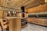 This stunning chalet boasts a rustic-chic kitchen with reclaimed wood cabinetry and a sleek black range hood.