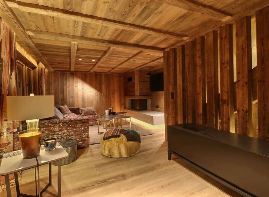 This stunning chalet boasts a cozy living area with exposed wooden beams and walls, creating a warm and inviting atmosphere.