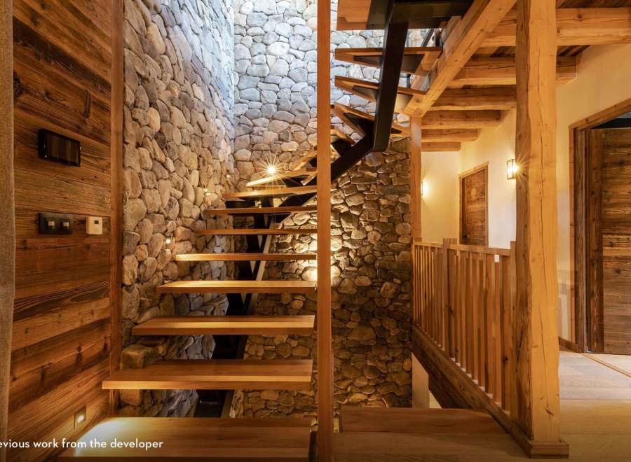 Discover the rustic charm of this stunning property, showcasing a beautifully designed staircase with stone walls and wooden accents.