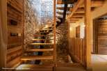 Discover the rustic charm of this stunning property, showcasing a beautifully designed staircase with stone walls and wooden accents.