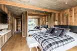 Experience rustic charm in this cozy bedroom, featuring warm wooden walls and a stylish plaid blanket.