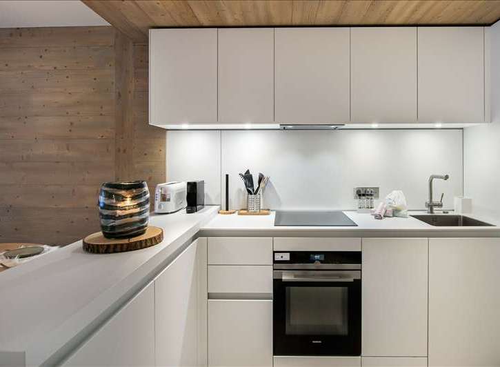 This modern kitchen boasts sleek white cabinetry and a minimalist design, perfect for a contemporary living space.