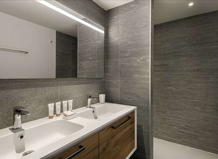 This modern bathroom features a sleek design with a double sink vanity and a large mirror.