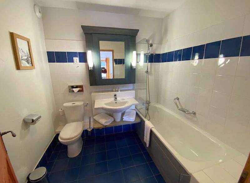 This bathroom features a clean and modern design with white tiles and a striking blue accent.