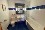 This bathroom features a clean and modern design with white tiles and a striking blue accent.