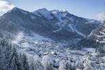 Discover a charming alpine village nestled amidst snow-covered mountains and dense pine forests.