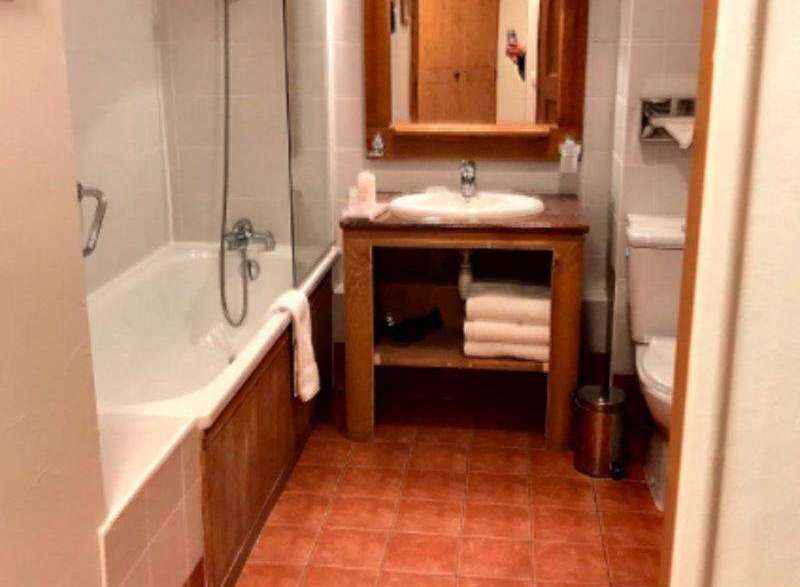 This charming bathroom features a cozy ambiance with its warm-toned tiles and wooden accents.