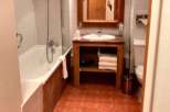 This charming bathroom features a cozy ambiance with its warm-toned tiles and wooden accents.