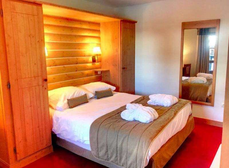 Cozy up in this charming bedroom featuring a warm wooden interior and a comfortable bed.